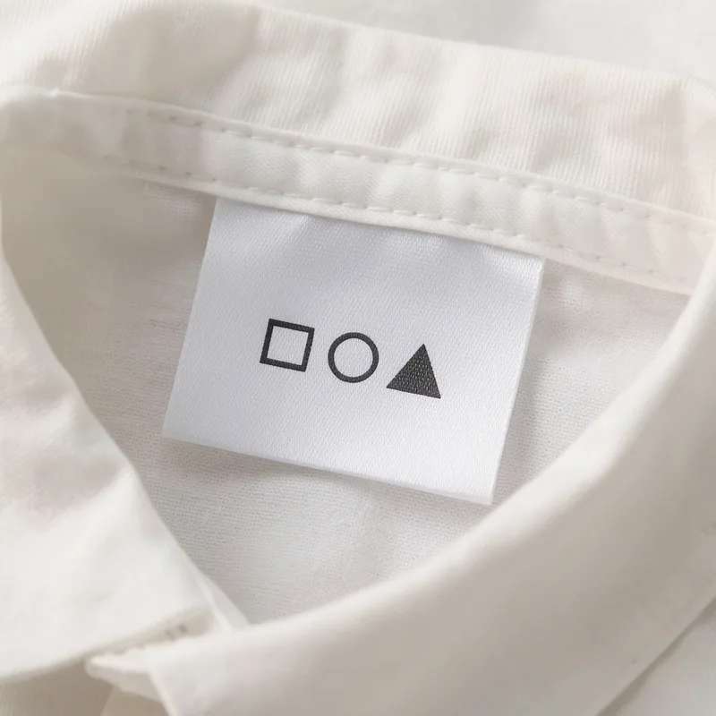 Gros plan sur une étiquette textile cousue, série de cinq pictogrammes d&rsquo;entretien nettement lisibles